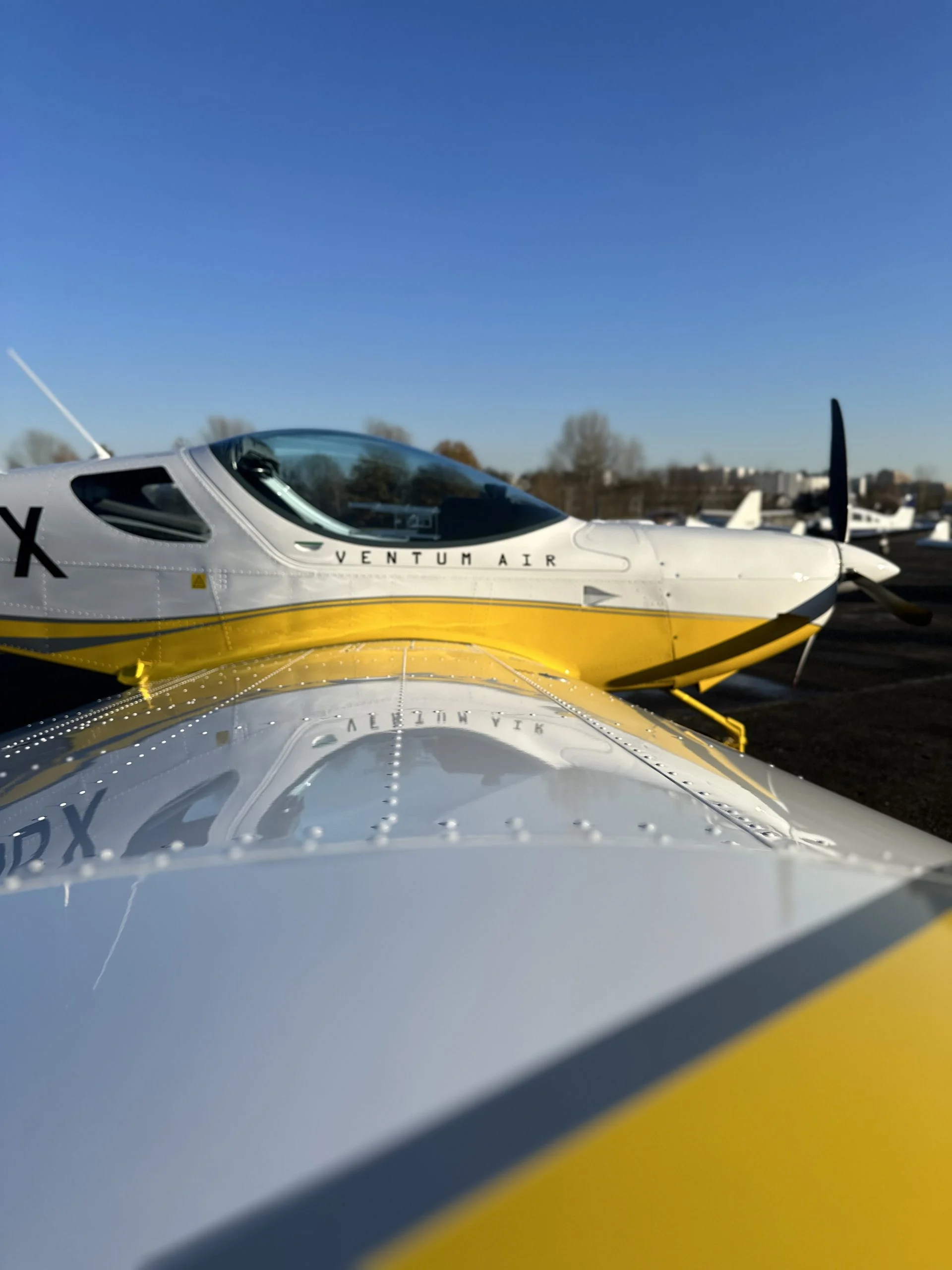 Ventum Air training aircraft on the apron, viewed over a wing